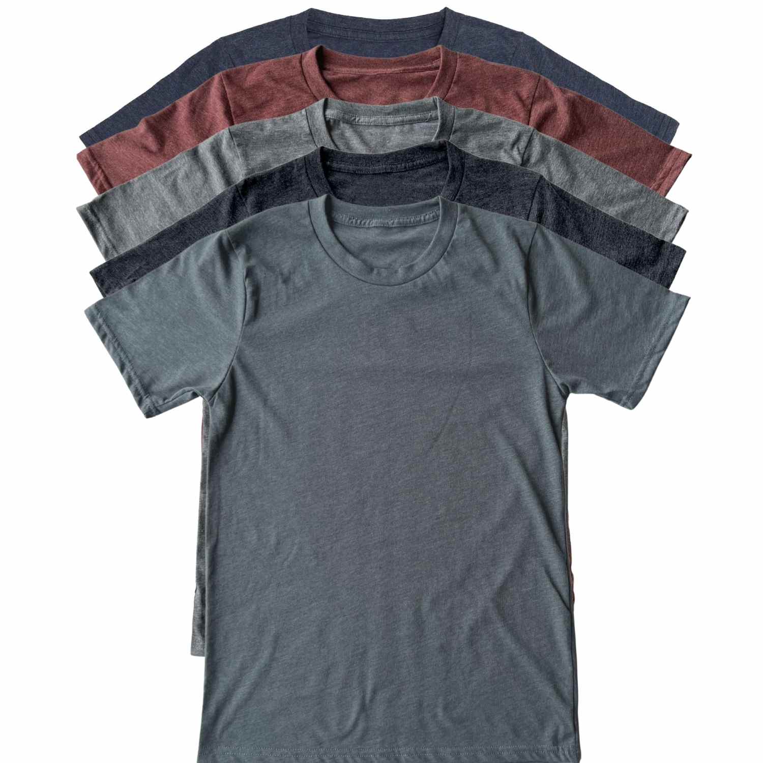 A stack of five short-sleeve crewneck t-shirts in different colors, arranged diagonally on a plain white background. The shirts are heather gray, heather navy, heather burgundy, heather charcoal, and heather navy. All our shirts are Made in USA