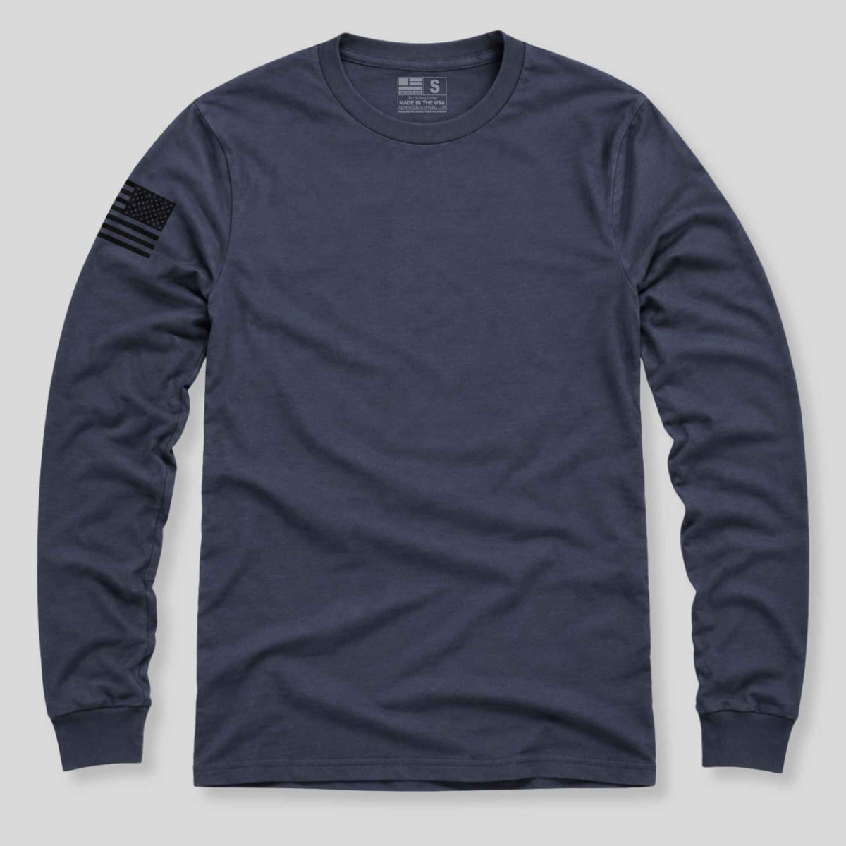 A navy blue long-sleeve crewneck t-shirt with a black American flag patch on the right sleeve, displayed flat against a light gray background.