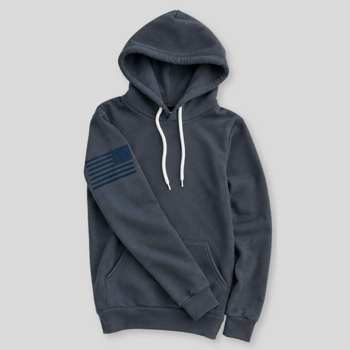 A dark gray hooded sweatshirt with white drawstrings and a navy blue distressed American flag graphic on the left sleeve, displayed against a solid light gray background.