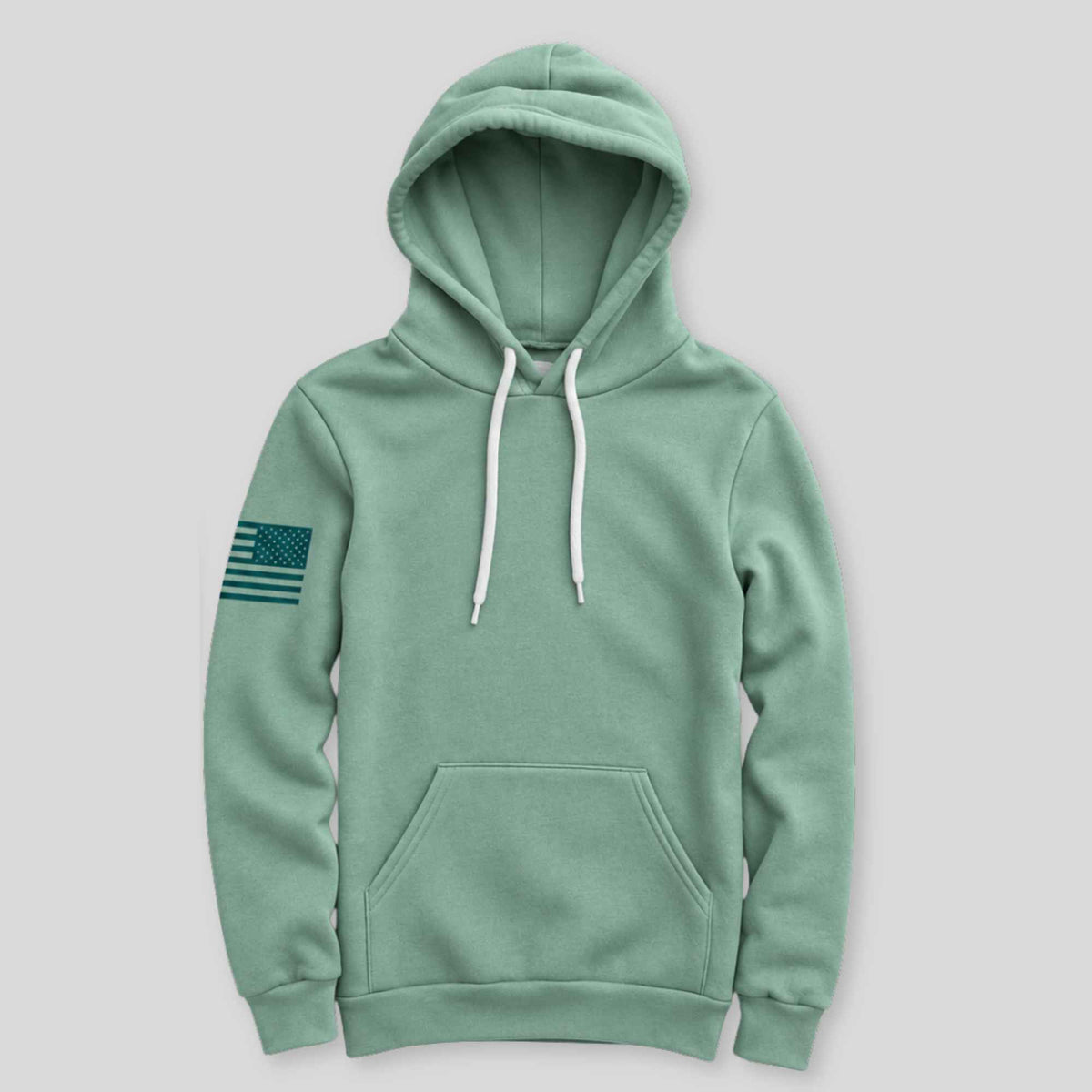 A sage green pullover hoodie with white drawstrings and a dark green American flag patch on the left sleeve, displayed against a solid light gray background.